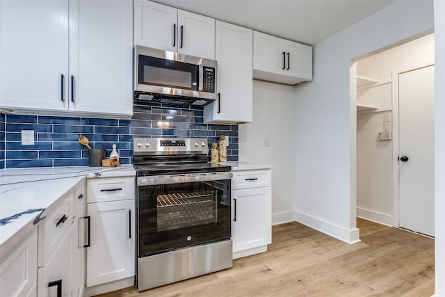 kitchen with stainless steel appliances, white cabinetry, light wood-style floors, light stone countertops, and tasteful backsplash