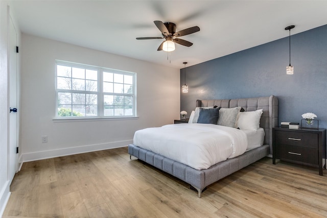 bedroom with light wood-type flooring, ceiling fan, and baseboards