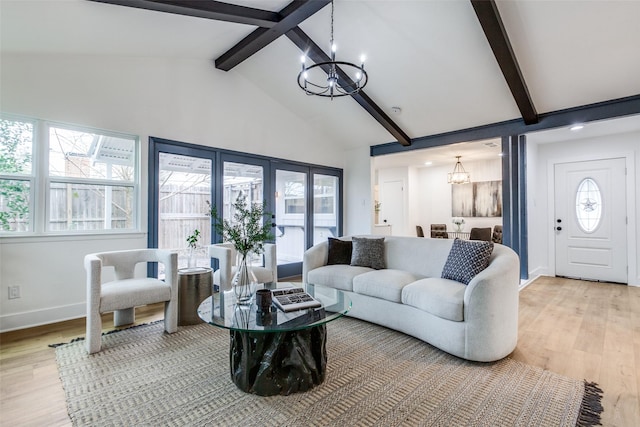 living room featuring a chandelier, light wood-type flooring, beam ceiling, and baseboards