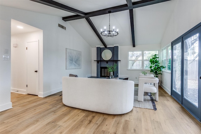 living area with light wood finished floors, visible vents, vaulted ceiling with beams, a brick fireplace, and a notable chandelier