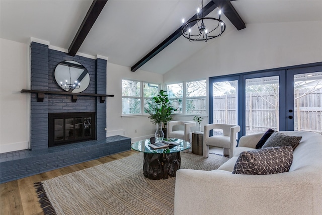 living area featuring a chandelier, a brick fireplace, wood finished floors, and baseboards