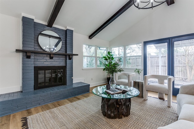 living area featuring a chandelier, a brick fireplace, wood finished floors, and beam ceiling