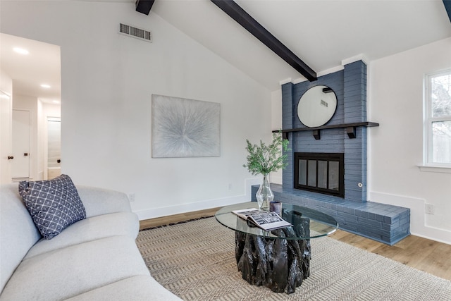 living room with visible vents, a fireplace, lofted ceiling with beams, and wood finished floors