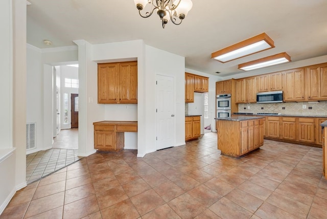 kitchen with built in desk, stainless steel appliances, visible vents, backsplash, and a kitchen island