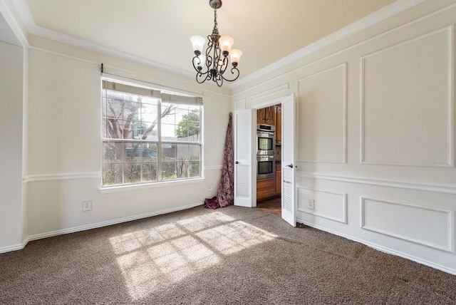 carpeted empty room with an inviting chandelier, ornamental molding, and a decorative wall