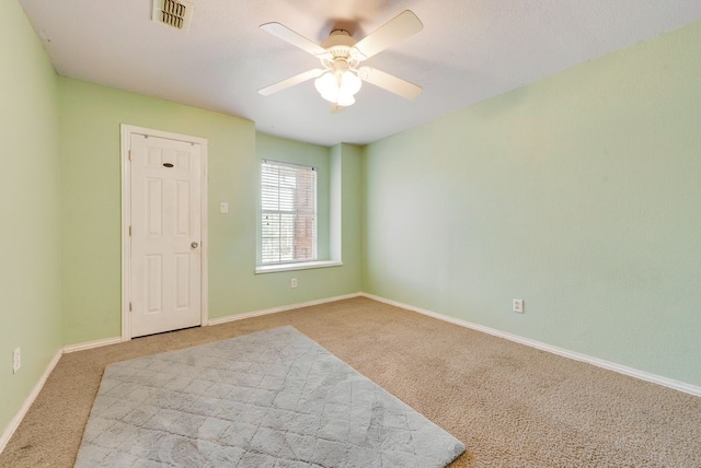 spare room featuring baseboards, ceiling fan, visible vents, and carpet flooring