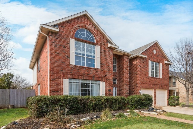 traditional-style house with concrete driveway, brick siding, and fence