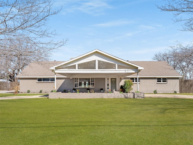 view of front of home with a front yard, brick siding, and fence