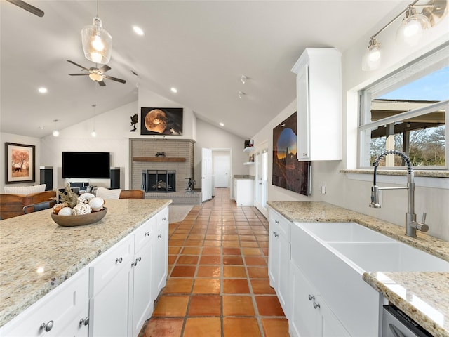 kitchen featuring a fireplace, a sink, white cabinetry, vaulted ceiling, and dishwasher