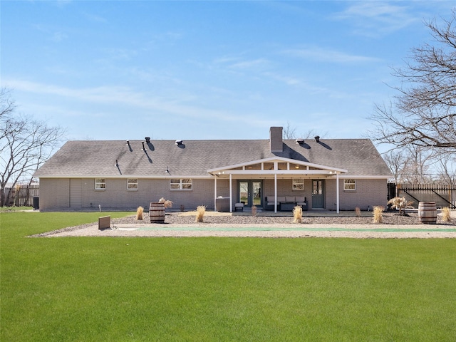 back of house with brick siding, a yard, a chimney, a patio, and a shingled roof