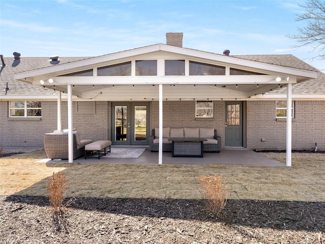 rear view of house featuring french doors, brick siding, a patio, and a chimney