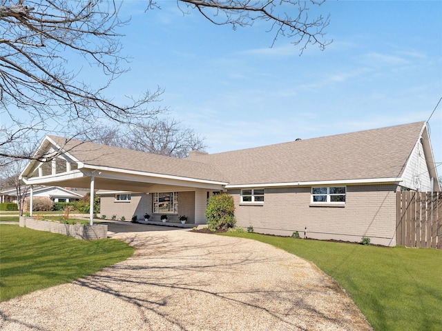 view of front of home with aphalt driveway, brick siding, a shingled roof, fence, and a front yard