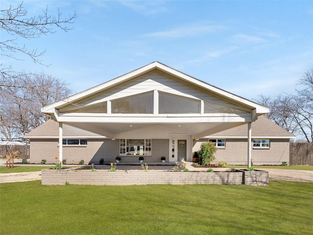 rear view of house featuring brick siding, fence, and a yard