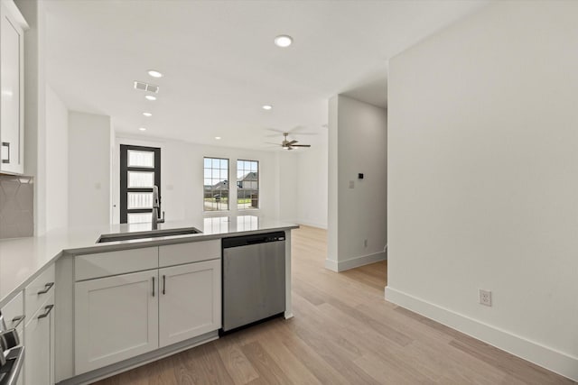 kitchen with visible vents, a peninsula, stainless steel dishwasher, white cabinetry, and a sink