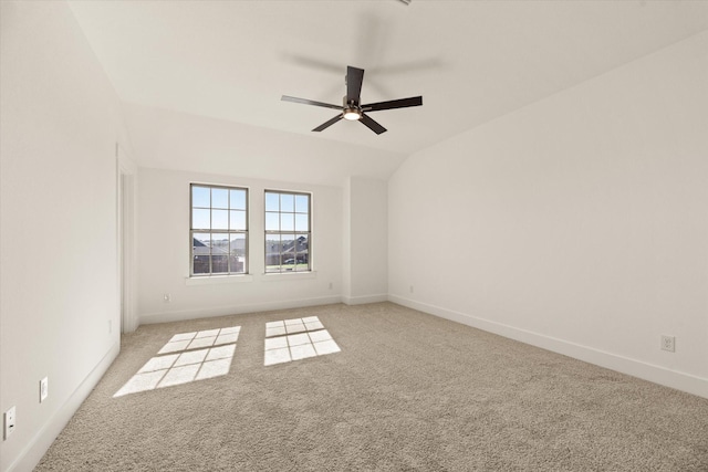 spare room featuring lofted ceiling, baseboards, a ceiling fan, and light colored carpet