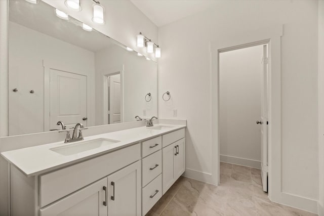 bathroom with double vanity, marble finish floor, baseboards, and a sink