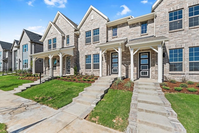 view of property featuring brick siding and a front lawn