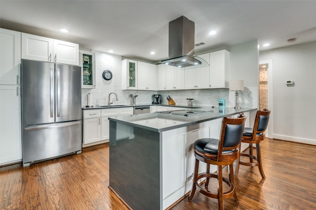 kitchen with island exhaust hood, dark wood-style floors, appliances with stainless steel finishes, and a breakfast bar