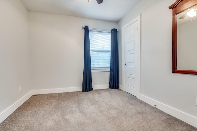 carpeted spare room featuring a ceiling fan and baseboards