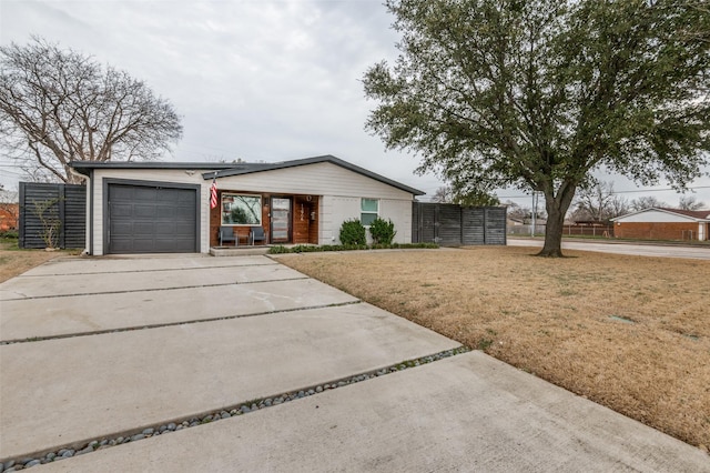 view of front of house with an attached garage, fence, driveway, roof mounted solar panels, and a front yard