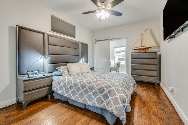 bedroom featuring hardwood / wood-style floors, a barn door, a ceiling fan, and baseboards