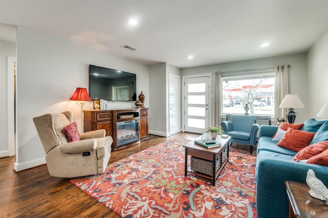 living room with visible vents, a glass covered fireplace, wood finished floors, recessed lighting, and baseboards