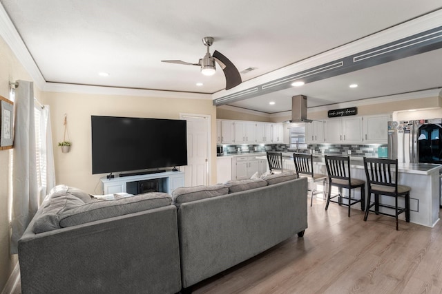 living area with a ceiling fan, recessed lighting, light wood-style flooring, and crown molding