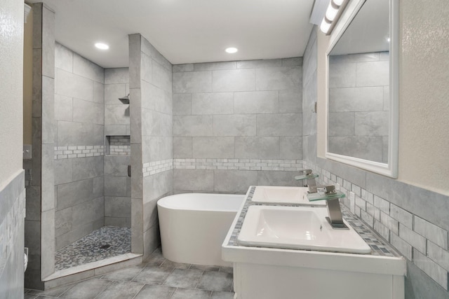 full bathroom featuring a freestanding tub, a sink, tile walls, and walk in shower