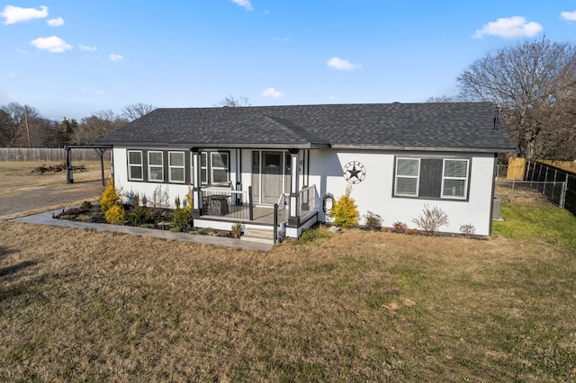 ranch-style house featuring a front yard, roof with shingles, and fence