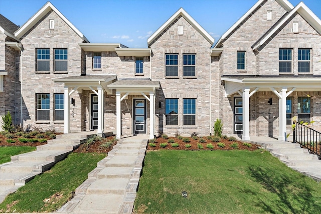 view of front of property with covered porch, brick siding, and a front lawn