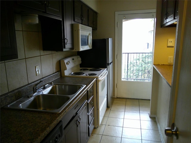 kitchen with light tile patterned flooring, white appliances, a sink, tasteful backsplash, and dark countertops