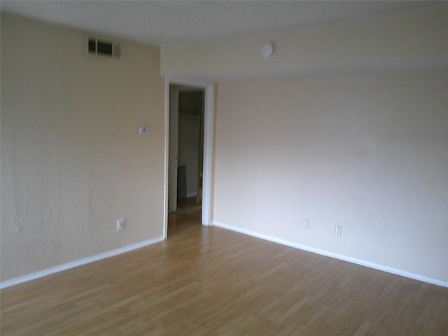 empty room featuring baseboards, visible vents, and wood finished floors