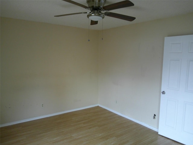 spare room featuring light wood-type flooring, baseboards, and a ceiling fan