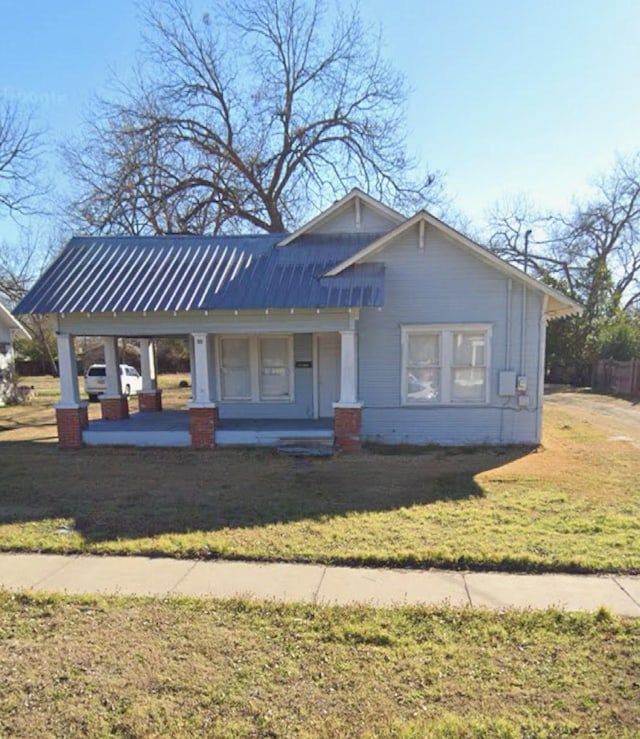 view of front of house featuring metal roof, a porch, a front lawn, and a carport