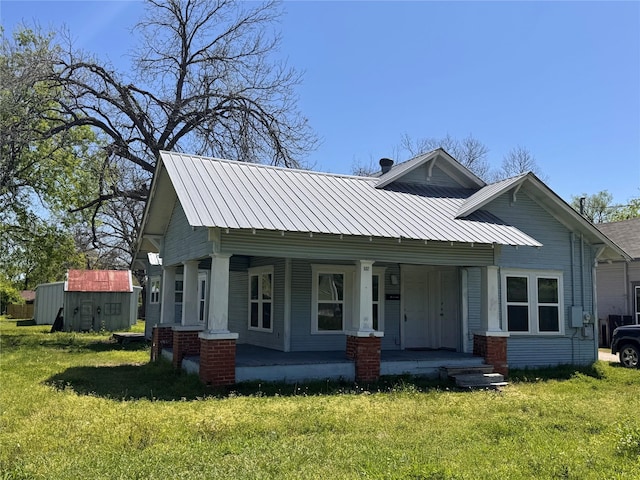 view of front facade featuring a front yard, metal roof, and covered porch