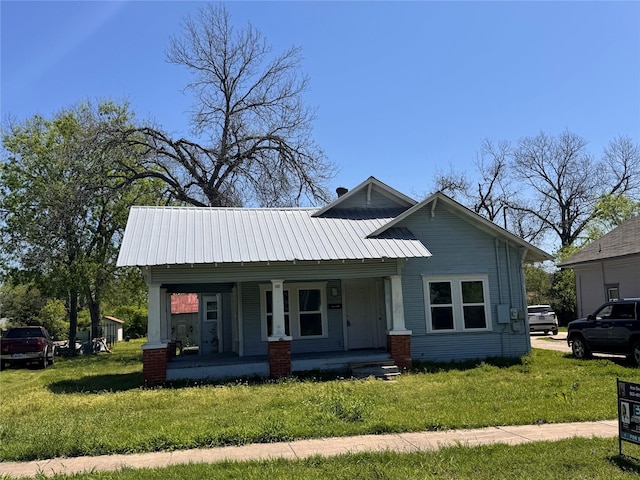 bungalow with covered porch, a front yard, and metal roof