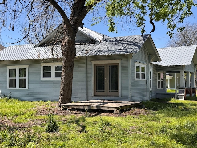 rear view of house featuring metal roof, french doors, and a wooden deck