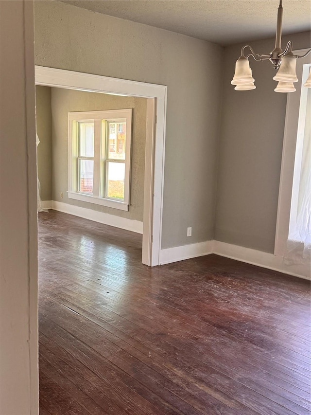 spare room featuring dark wood-type flooring, baseboards, and a textured ceiling