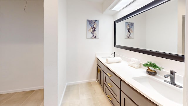 bathroom with tile patterned flooring, a sink, baseboards, and double vanity