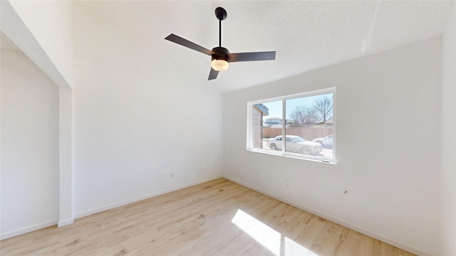 unfurnished room with baseboards, a ceiling fan, lofted ceiling, wood finished floors, and a textured ceiling