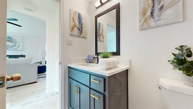 bathroom featuring toilet, ceiling fan, wood finished floors, and vanity