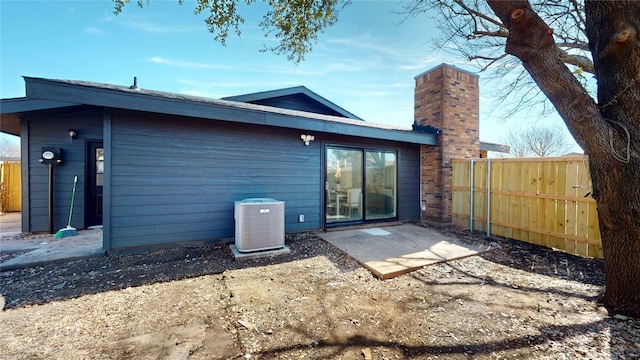 back of property featuring central AC, a chimney, and fence