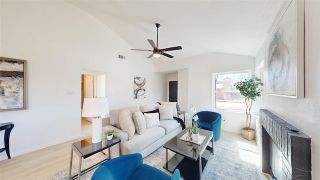 living room with ceiling fan, wood finished floors, visible vents, baseboards, and vaulted ceiling