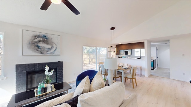 living room featuring vaulted ceiling, light wood finished floors, a fireplace, and baseboards