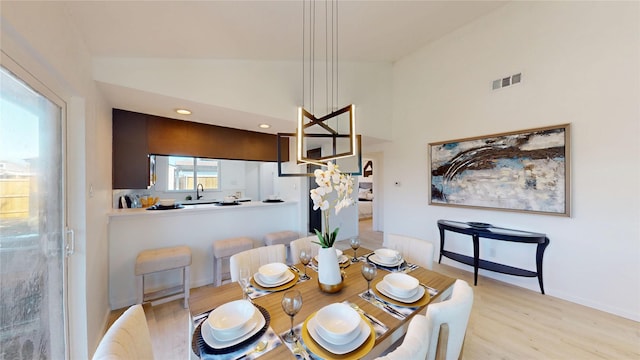 dining space with lofted ceiling, visible vents, and light wood finished floors