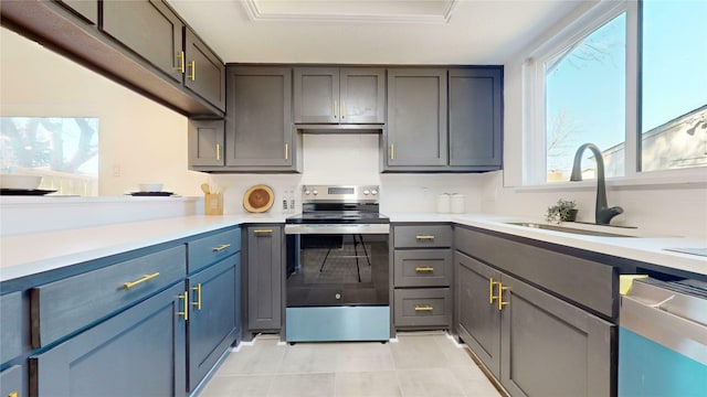 kitchen with light tile patterned floors, a sink, light countertops, stainless steel range with electric cooktop, and backsplash