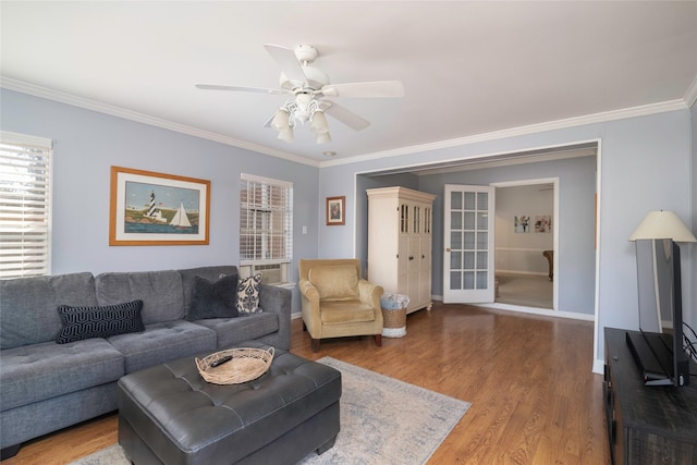 living room with baseboards, ceiling fan, ornamental molding, and wood finished floors