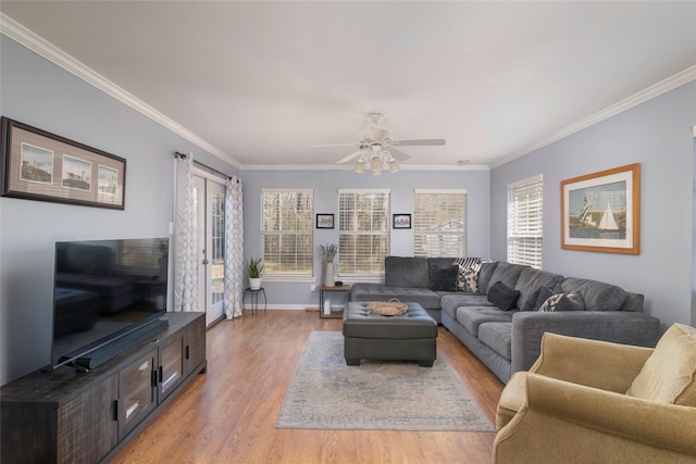 living area featuring light wood finished floors, baseboards, ornamental molding, and a ceiling fan