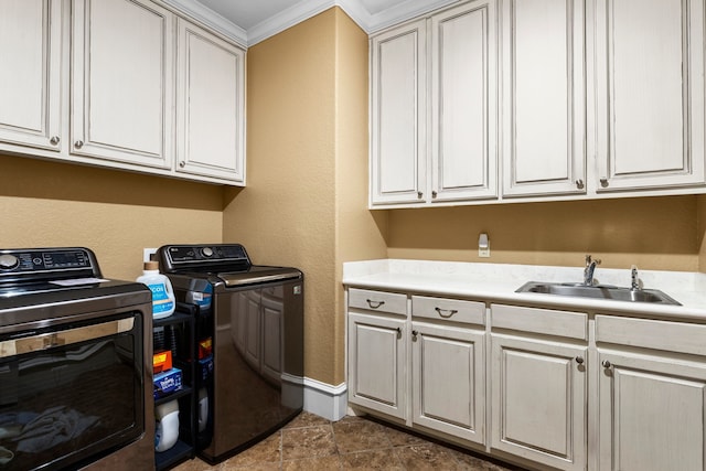 laundry area featuring crown molding, washing machine and clothes dryer, cabinet space, a sink, and baseboards