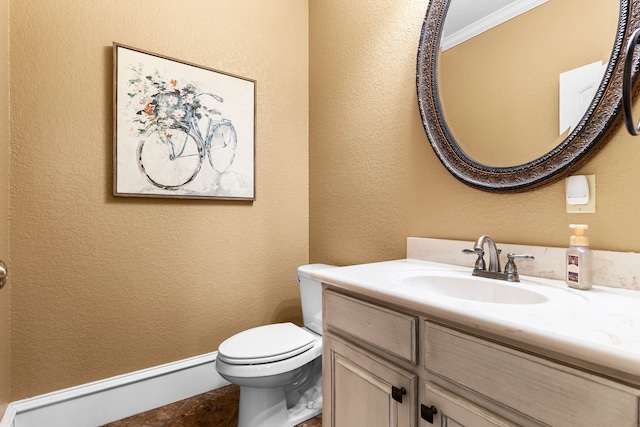 half bathroom featuring baseboards, a textured wall, vanity, and toilet